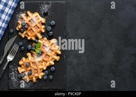 Cialde belghe con frutti di bosco e zucchero su sfondo di ardesia, vista dall'alto con copia spazio per il testo Foto Stock