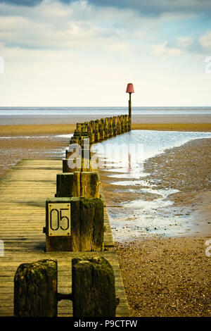 Vecchio groyne in legno per la difesa del mare su una spiaggia di ciottoli che guarda al mare, England, Regno Unito Foto Stock