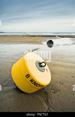 Boa di avvertimento su un wet spiaggia sabbiosa a bassa marea, England, Regno Unito Foto Stock
