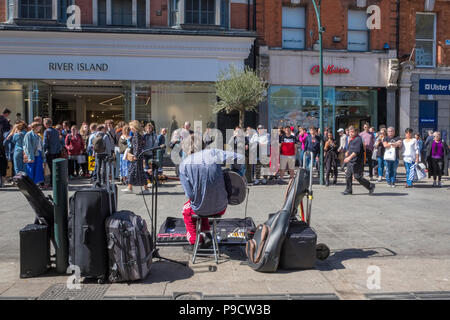 Un busker musicista,con una folla di persone che guardano il performer di Grafton Street, Dublin, Irlanda, Europa Foto Stock