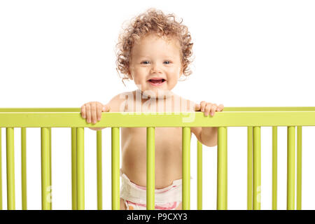 Baby boy in un lettino guardando la telecamera e sorridente isolati su sfondo bianco Foto Stock