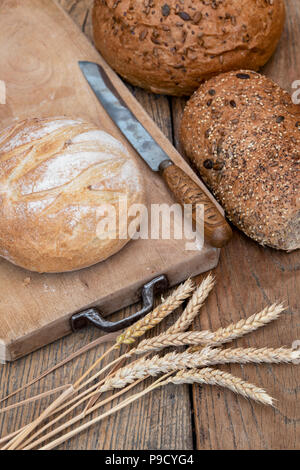 Pane bianco e pani seminate su una scheda di pane di grano e di un coltello per pane. Regno Unito Foto Stock