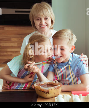 Ritratto di nonna felice con i suoi nipoti divertirsi durante la cottura biscotti al cioccolato Foto Stock