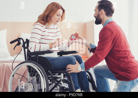 Calma uomo in piedi sul suo ginocchio e chiedendo la sua ragazza a sposare lui Foto Stock