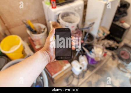 Mano trattiene un telefono cellulare su un lato della costruzione Foto Stock