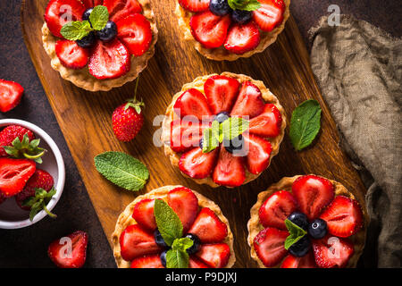 Crostata di fragole con crema pasticcera e frutti di bosco freschi sul buio tavolo arrugginita. Vista dall'alto. Foto Stock