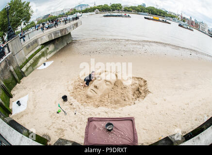 Street photography immagine di un artista maschile facendo una scultura di sabbia sulle rive del fiume Tamigi a Londra Foto Stock