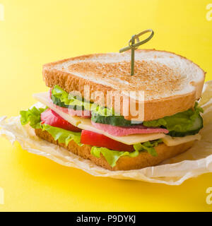 Sandwich con formaggio, prosciutto e verdure fresche in un giallo sfondo luminoso Foto Stock