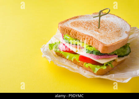Sandwich con formaggio, prosciutto e verdure fresche in un giallo sfondo luminoso Foto Stock