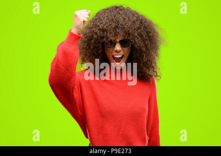 African American donna che indossa gli occhiali da sole irritato e arrabbiato esprimendo emozione negativa, arrabbiato con qualcuno Foto Stock