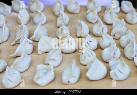 Più cinese gnocco crudo posto sulla tavola di legno. Gnocco è chiamato Jiaozi in cinese, è un popolare cinese tradizionale cibo. Foto Stock