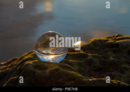 Sfera di cristallo fotografia - Sunset beach, sfera su una roccia Foto Stock