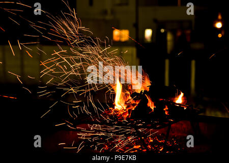 Il posto del fuoco su una notte estiva che mostra i dettagli delle scintille e fiamme risplende nelle tenebre della notte Foto Stock