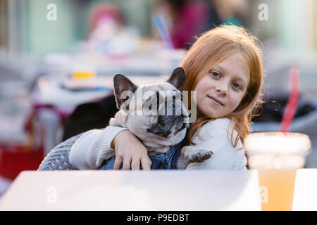 Giovane e bella ragazza redhead holding adorabili fawn bulldog francese. Foto Stock