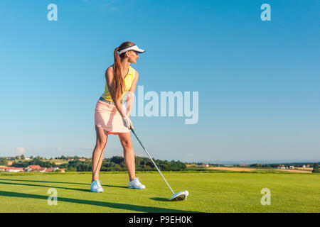 Professionista di golf femminile player sorridente durante l'oscillazione un autista di club Foto Stock