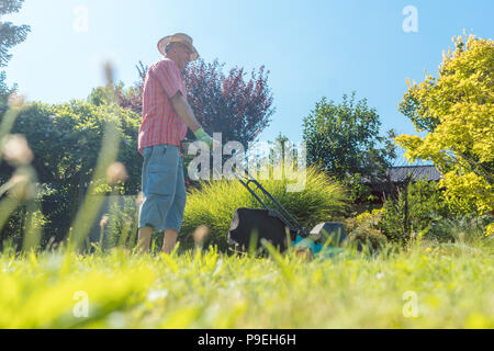 Active senior uomo sorridente mentre si utilizza un taglio di erba macchina Foto Stock