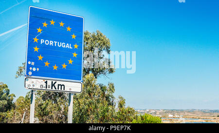 Cartello stradale sul confine di un paese dell'Unione europea, il Portogallo a 1 km avanti con blue sky copia spazio. Incrocio sulla autostrada dalla Spagna. Foto Stock