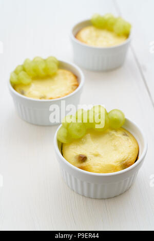 Mini zapekankas (cotta dessert quark) con uvetta e uva fresca. Bianco tavola di legno, ad alta risoluzione Foto Stock