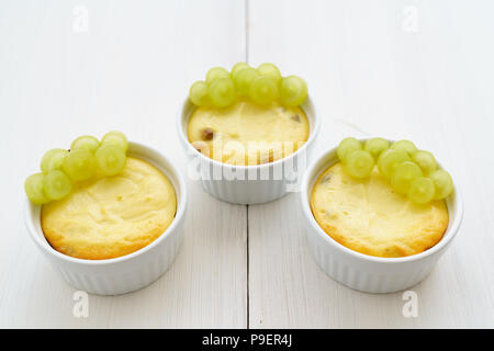 Mini zapekankas (cotta dessert quark) con uvetta e uva fresca. Bianco tavola di legno, ad alta risoluzione Foto Stock