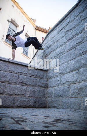 Giovane uomo facendo un incredibile parkour trucco sulla strada. Foto Stock