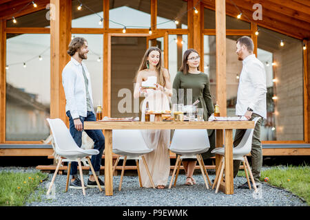 Amici con bevande sul cortile della casa Foto Stock