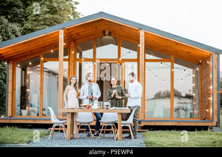 Amici con bevande sul cortile della casa Foto Stock