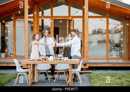 Amici con bevande sul cortile della casa Foto Stock