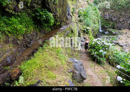 Una donna che cammina su un sentiero costiero sulla costa nord di Sao Miguel, Azzorre Foto Stock