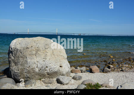 McGulpin Rock è stato uno strumento di navigazione nei rettilinei di Mackinaw per secoli. Il ponte Mackinac è in distanza. Foto Stock