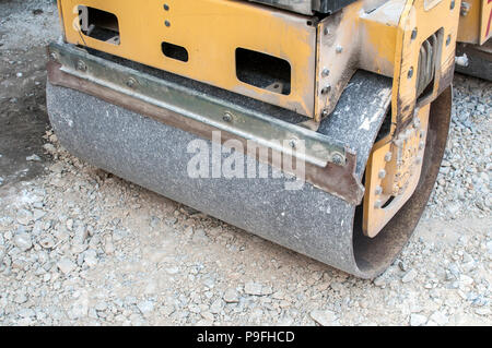 Dettaglio della piccola strada di lavoro del rullo in corrispondenza di strada in costruzione la compattazione della fondazione di ghiaia per via della città Foto Stock