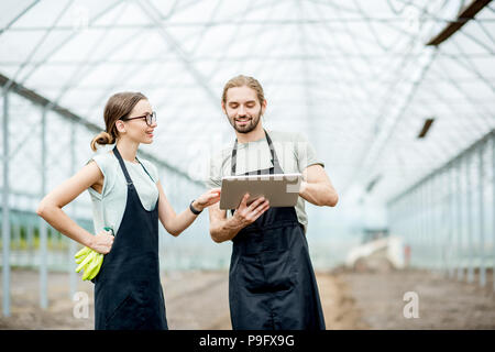 Gli agricoltori con la compressa in serra Foto Stock