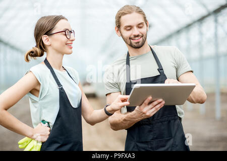 Gli agricoltori con la compressa in serra Foto Stock