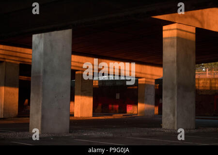 Il degrado urbano - luce solare residua e colore in un vuoto di parcheggio sotto un cavalcavia. Essex, Gran Bretagna. Foto Stock