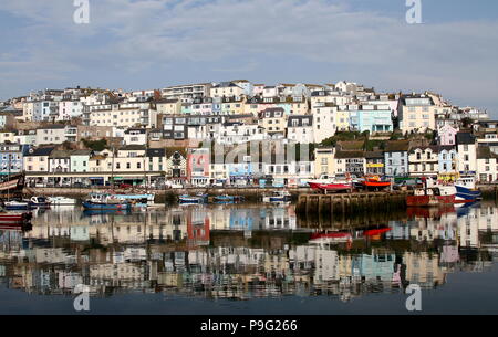 Brixham, Devon, Inghilterra: riflessione inquadratura del villaggio di pescatori case nel porto di acqua su una mattina di sole Foto Stock