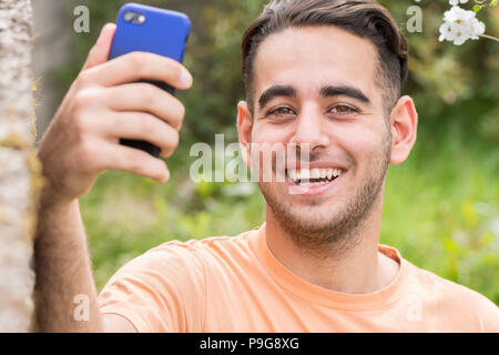 Felice giovane uomo godere e prendendo un selfie all area all'aperto nella primavera del tempo Foto Stock