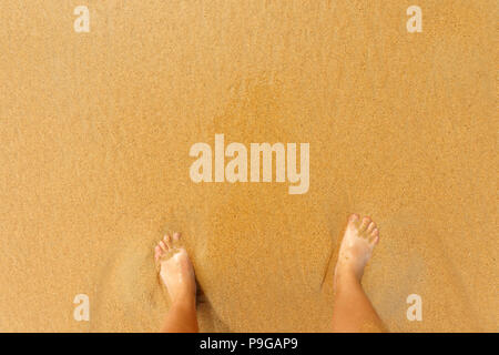 Un uomo si erge sulla sabbia, uomini i piedi sulla sabbia. Concetto di vacanza con spazio di copia Foto Stock
