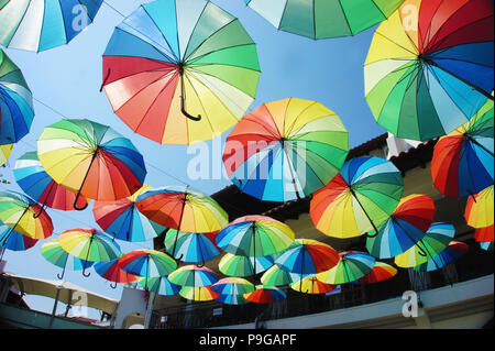 Gruppo di ombrelloni colorati al di sopra della strada nel cielo Foto Stock