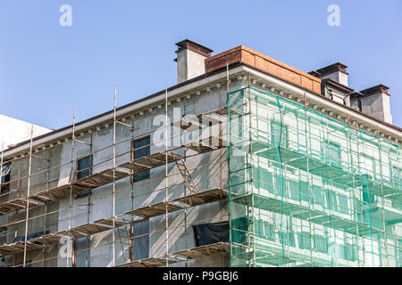 Facciata di un edificio ristrutturato. ponteggio verde con rete di protezione Foto Stock