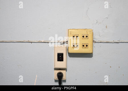 Vecchio e polvere elettricità prese e interruttori con filo su grunge parete blu Foto Stock