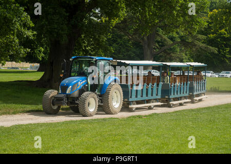 I visitatori che arrivano a showground, trasportati dal parcheggio nelle carrozze trainato dal trattore blu - RHS Chatsworth Flower Show, Derbyshire, Inghilterra, Regno Unito. Foto Stock