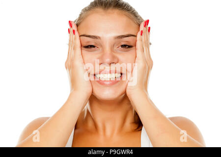 Giovane donna sorridente stringe il viso tra le mani Foto Stock