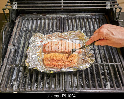 La cottura di salmone e bianco i filetti di pesce su un grill all'aperto utilizzando la stagionatura. Foto Stock