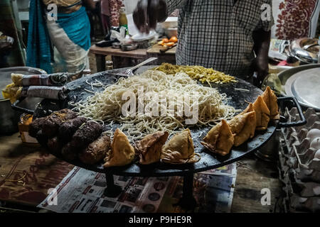 Indian street food rendendo di vegetariano tagliatelle. l uomo è la frittura tagliatelle sulla strada. Goa in India. vari tipi di cibo di strada del tostatore. Foto Stock