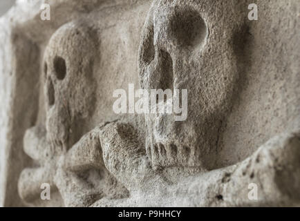 Antico casale in pietra con cranio crossbones. Scultura antica. Ideale per i concetti e gli sfondi. Foto Stock