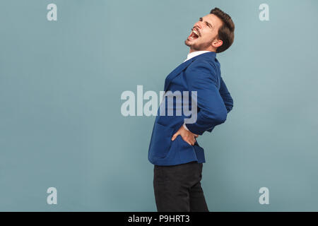 L uomo ha dolori di schiena. Pietre o reni organi. ritratto di bello barbuto imprenditore in tuta blu e una camicia bianca. Piscina studio shot, isolati o Foto Stock