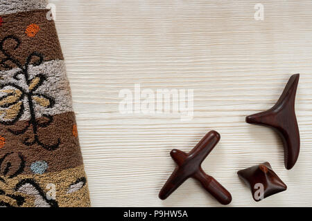 Verniciato bianco sullo sfondo di legno con asciugamani in spugna e scolpiti in legno bastoncini di massaggio e con copia spazio. Foto Stock