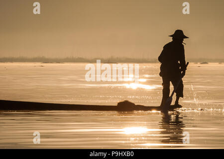 Silhouette di un pescatore in Myanmar (Birmania) sul Lago Inle durante il sunrise per la cattura di pesce Foto Stock