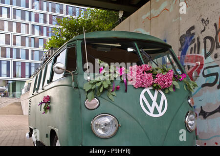 Bremen, Germania - Luglio 17th, 2018 - Verde VW T3 van con grandi bianchi logo VW con una moderna facciata in vetro e in background Foto Stock