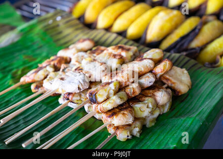 Fetta alla griglia spiedini di Banana su verde foglia di banano, in Thailandia e di stile tradizionale. Banana Thai dessert Foto Stock