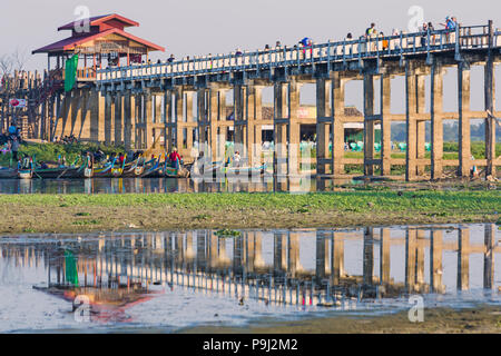 I turisti che attraversano il Ponte U Bein, il Ponte di Ubein, sul Lago Taungthaman, Amarapura, Mandalay, Myanmar (Birmania) Asia nel mese di febbraio - riflesso nel lago Foto Stock